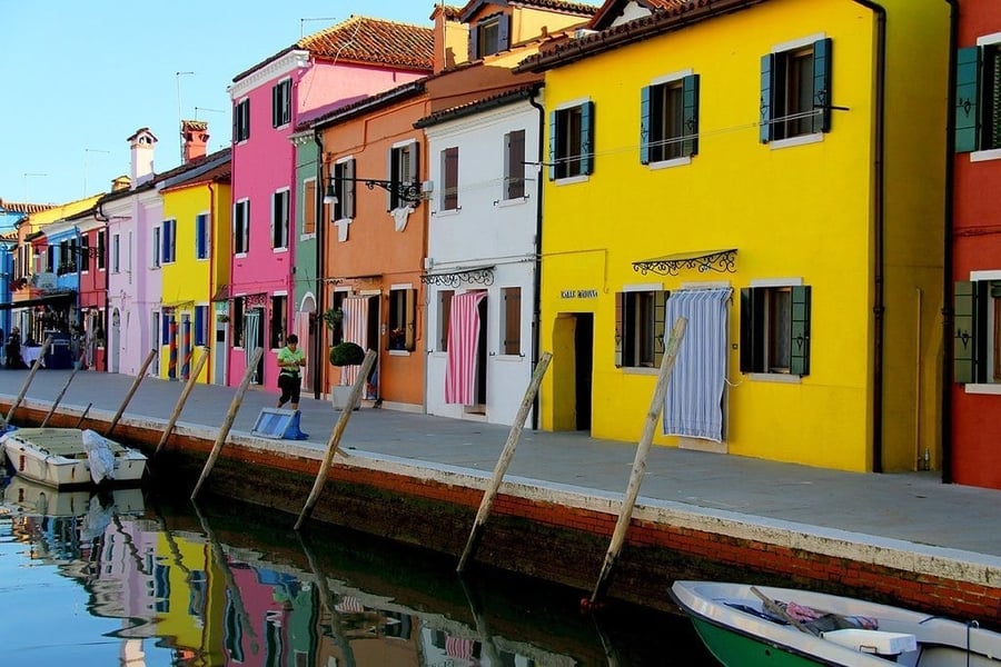 Le facciate sul canale — Rosa, verde e giallo acceso, riflessi nell'acqua ferma