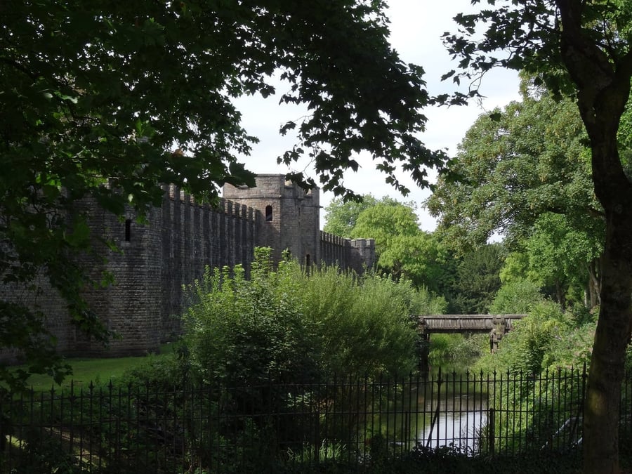Cardiff Castle — Le mura del castello tra gli alberi, affacciate su un canale nel cuore della città