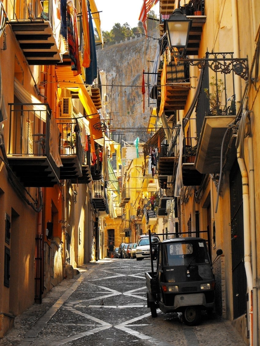Un vicolo del centro storico — Panni stesi da un balcone all'altro, tra case color ocra e la Rocca sullo sfondo
