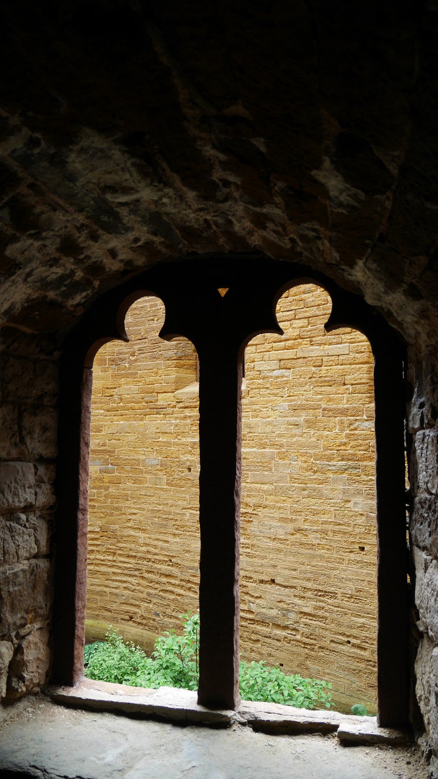 Una finestra nelle mura — Un'apertura bifora che guarda sulla muratura in arenaria del castello
