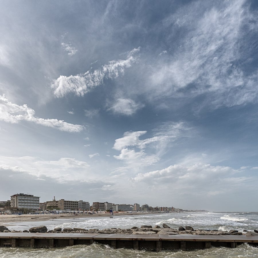 La costa vista dal molo — Nuvole a pennellate sopra lo skyline balneare