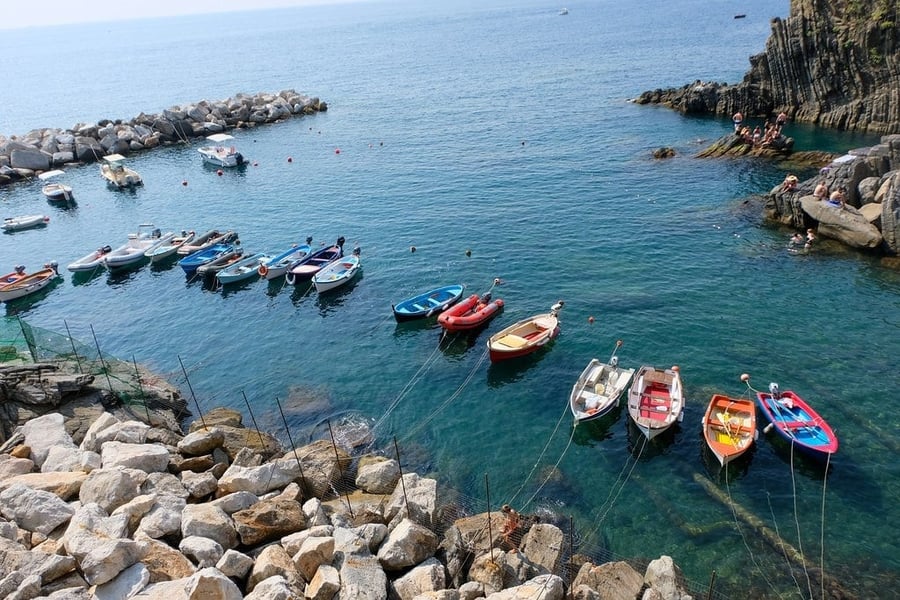 Le barche nella cala — Acque turchesi e barche colorate tra gli scogli