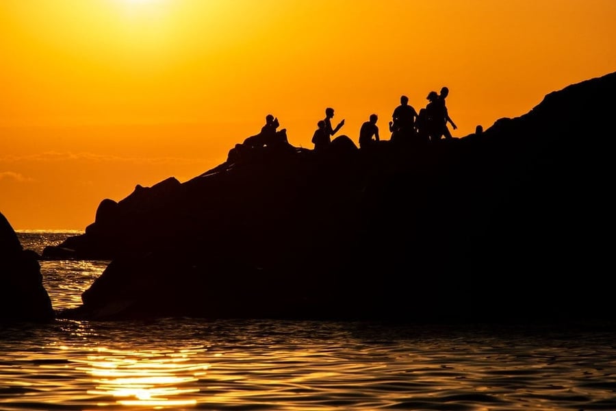 Gli scogli al tramonto — Sagome controluce su un cielo acceso d'arancio