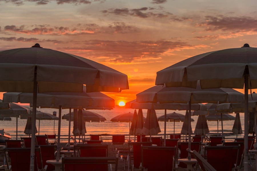 L'alba tra gli ombrelloni — Il sole che sale sull'Adriatico, visto dalle file degli stabilimenti