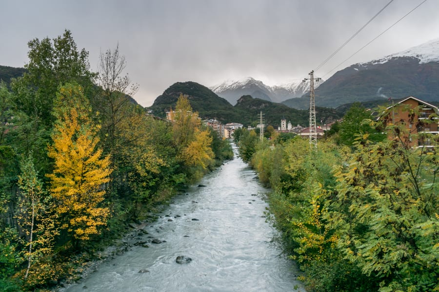 La Dora Riparia — Il torrente alpino che attraversa la città, con la valle e le cime innevate sullo sfondo