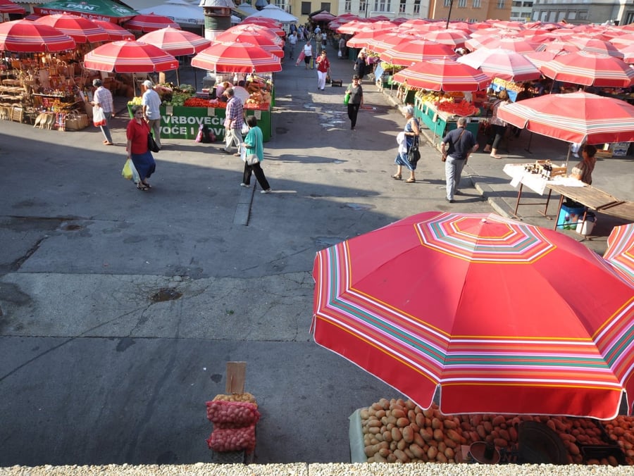Il mercato di Dolac — Ombrelloni rossi sopra le bancarelle di frutta e verdura